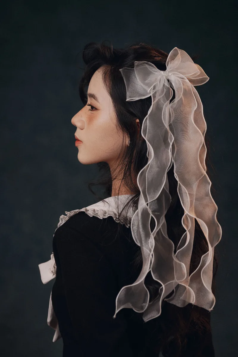 The coquette aesthetic, a woman wearing a large organza hair bow with a lace collar