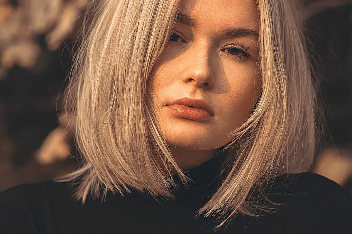 A woman with a blonde bob cut just below the jaw, the front lengths falling forward past her chin