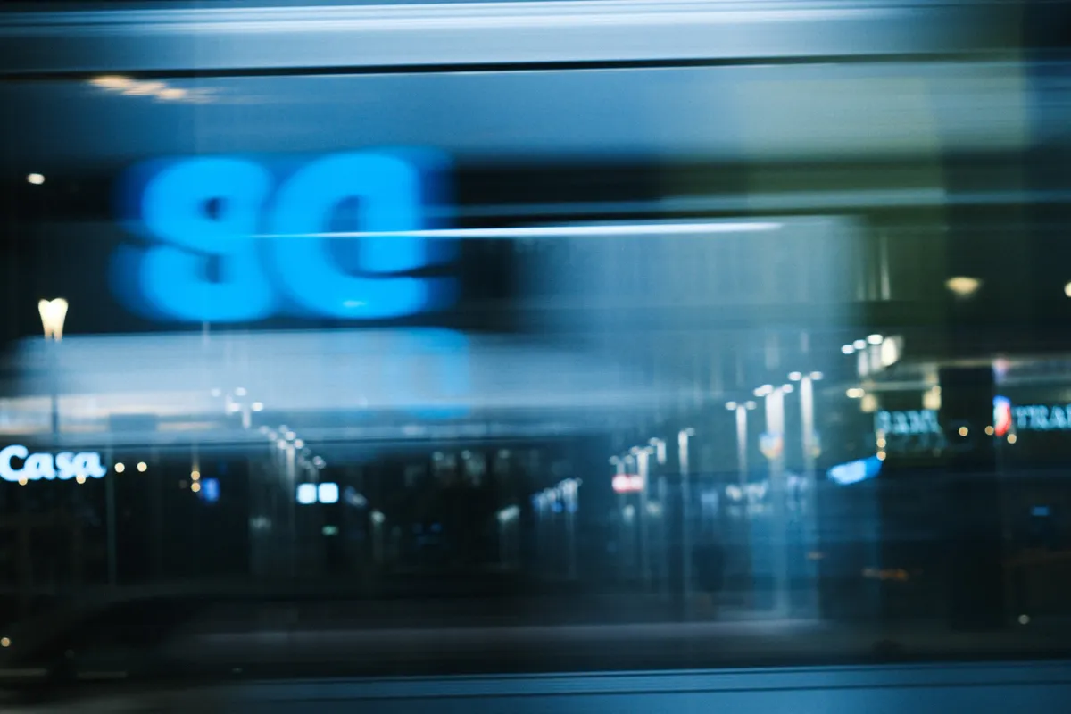 A night street and a lit shop sign smeared sideways by camera movement