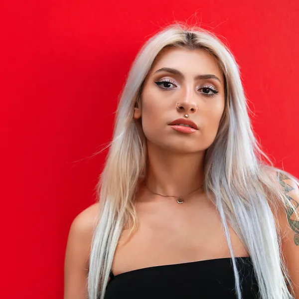 Woman with icy platinum blonde hair standing against a red wall