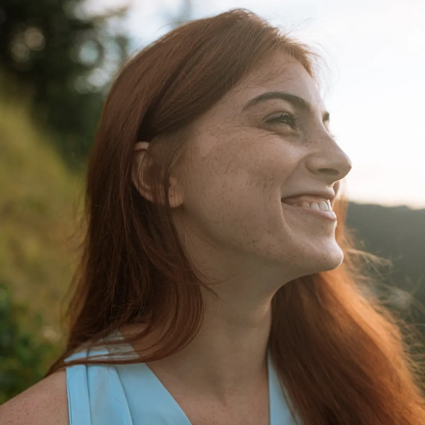 Woman with coppery auburn hair smiling in warm evening sunlight